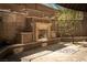 An outdoor living space showcases a fireplace with seating, brick pavers, and mature landscaping at 1800 Melfi Ct, Henderson, NV 89012