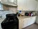 Well-lit kitchen features a black gas stove, stainless vent, white cabinets, mosaic backsplash, and granite countertops at 5157 New Bedford Dr, Las Vegas, NV 89122