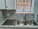 Close-up of a stainless steel sink with tile backsplash and natural light from window at 5157 New Bedford Dr, Las Vegas, NV 89122