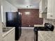 Kitchen featuring black appliances, brick accent wall and stainless steel sink at 5157 New Bedford Dr, Las Vegas, NV 89122