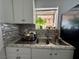 A kitchen sink below a window is flanked by white cabinets and a black refrigerator at 5157 New Bedford Dr, Las Vegas, NV 89122