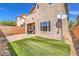 Backyard showcasing lush artificial turf, brick accents, and the home's exterior with windows at 10509 Hartford Hills Ave, Las Vegas, NV 89166