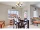 Bright dining area with a dark wood table and chairs, complemented by a modern chandelier and natural light at 10509 Hartford Hills Ave, Las Vegas, NV 89166