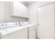 Laundry room with white washer and dryer, overhead storage cabinets and an exterior access door at 133 Park Ridge Ln, Henderson, NV 89002