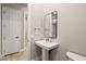Modern half bathroom with pedestal sink, rectangle mirror, and wood-style floors at 2264 Savannah River St, Henderson, NV 89044