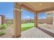 Covered back patio with brick pavers overlooking putting green and low maintenance desert landscaping at 244 Native Stone St, Las Vegas, NV 89138