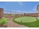 Backyard featuring putting green, desert landscaping, metal fence, and neighborhood views at 244 Native Stone St, Las Vegas, NV 89138