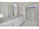 Bright bathroom with double sinks, white cabinets, and glass-enclosed shower with marble-look tile at 244 Native Stone St, Las Vegas, NV 89138