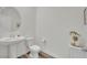 Powder room featuring a pedestal sink, toilet, round mirror, and gray wood-look flooring at 244 Native Stone St, Las Vegas, NV 89138