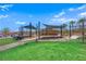 A shaded park with a small building, play structures, and lush green spaces for relaxing and playing at 244 Native Stone St, Las Vegas, NV 89138