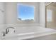 Close up view of a soaking tub with a sleek faucet and a window with neighborhood views at 2581 Tolmezzo St, Henderson, NV 89044