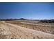Wide angle shot looking at a dry landscape and neighborhood in the distance under a bright blue sky at 2581 Tolmezzo St, Henderson, NV 89044
