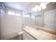 Bright bathroom with a shower-tub combination, white tile, granite countertop and a large mirror over vanity at 3025 Yankee Clipper Dr, Las Vegas, NV 89117