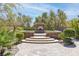 Outdoor fireplace sitting area with stone accents and lush landscaping, a perfect place for gatherings at 5410 Serenity Brook Dr, Las Vegas, NV 89149