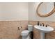 Charming powder room featuring a pedestal sink, decorative mirror, and stone accents at 5410 Serenity Brook Dr, Las Vegas, NV 89149