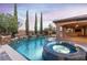 Relaxing backyard with a pool and hot tub, complemented by lush landscaping and an outdoor entertainment area at 5410 Serenity Brook Dr, Las Vegas, NV 89149
