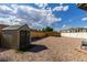 The gravel backyard includes a storage shed and a brick pathway, with fencing and small trees in the distance at 5865 Egan Crest Dr, Las Vegas, NV 89149