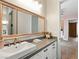 This bathroom has a large mirror, gray countertops, white cabinets and carpet floors at 5865 Egan Crest Dr, Las Vegas, NV 89149