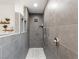 Modern shower featuring grey stone tiles, pebble floor, and multiple shower heads for a spa-like experience at 5865 Egan Crest Dr, Las Vegas, NV 89149