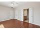 Bright bedroom featuring hardwood floors, ceiling fan, and a bathroom with double door access at 6059 Wheat Penny Ave, Las Vegas, NV 89122