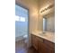 Bathroom featuring a wooden vanity, large mirror, and a door to the toilet and shower at 632 Hitchen Post Dr, Henderson, NV 89011