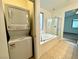 Bright bathroom featuring a soaking tub and separate shower with a stacked washer/dryer unit at 7253 Blooming Jasmine Ave, Las Vegas, NV 89117