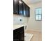 Laundry room featuring dark cabinets, a window and tile flooring at 7253 Blooming Jasmine Ave, Las Vegas, NV 89117