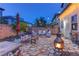 Well-lit backyard patio featuring pavers, a fire pit, lush greenery, and inviting seating areas at 10422 Prairie Mountain Ave, Las Vegas, NV 89166