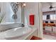 A luxurious soaking tub sits beneath a window with modern fixtures and decor in a relaxing spa-like bathroom at 10422 Prairie Mountain Ave, Las Vegas, NV 89166