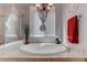 Relaxing bathroom with a soaking tub, natural light, and decorative chandelier at 10422 Prairie Mountain Ave, Las Vegas, NV 89166