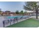 Community pool view with lounge chairs on concrete and artificial turf, surrounded by mature trees at 10422 Prairie Mountain Ave, Las Vegas, NV 89166