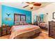 Vibrant bedroom featuring unique wall decor, ceiling fan, a mirrored closet and tile floors at 1253 Country Club Dr, Laughlin, NV 89029
