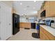 Kitchen boasts tile floors, natural wood cabinets, modern black appliances, and plenty of counter space at 2091 Waterton Rivers Dr, Henderson, NV 89044