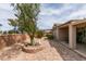 Relaxing backyard featuring a covered patio with seating, manicured trees, and rock landscaping at 2180 Tiger Links Dr, Henderson, NV 89012