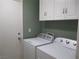 Well-lit laundry room features a washer, dryer, and overhead cabinets for storage at 2381 Lilac Cove St, Las Vegas, NV 89135