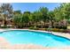 Community pool surrounded by trees, shrubs, and community buildings at 2451 N Rainbow Blvd # 1016, Las Vegas, NV 89108