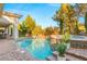 Beautiful pool and spa with waterfall feature surrounded by lush landscaping and brick pavers at 28 Tea Olive Dr, Las Vegas, NV 89141