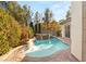 Backyard pool with rock waterfall feature surrounded by lush greenery and a paved patio at 28 Tea Olive Dr, Las Vegas, NV 89141