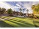 Spacious backyard with putting green, pool with rock waterfall, covered bar, and mature palm trees at 382 Chaplin Cove Ave, Las Vegas, NV 89183