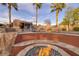 Custom fire pit adjacent to rock waterfall and pool creates a cozy ambiance, perfect for entertaining at 382 Chaplin Cove Ave, Las Vegas, NV 89183