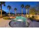 Custom pool with rock waterfall, spa, and swim up bar, lit by glowing lights in the evening at 382 Chaplin Cove Ave, Las Vegas, NV 89183