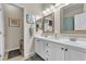 Bathroom featuring double sinks, framed mirrors, coastal artwork and under cabinet storage at 4624 Ventana Rey St, North Las Vegas, NV 89081
