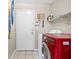 This laundry room features tile floors, a red washing machine, storage shelf, and wall-mounted surf boards for decor at 5224 Red Vine St, North Las Vegas, NV 89031