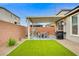 A cozy backyard patio with artificial turf, outdoor seating, and a grill under a covered area at 5479 Tamar Ridge Ct, Las Vegas, NV 89141