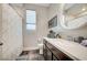 Bathroom with dark cabinets, white counters, a round mirror and a window at 5479 Tamar Ridge Ct, Las Vegas, NV 89141