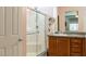 Well-lit bathroom with a glass shower, wooden vanity, neutral walls and tile flooring at 6317 Highledge St, North Las Vegas, NV 89081