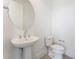 A clean powder room with a pedestal sink, round mirror, and modern toilet at 647 Spotted Falcon St, Las Vegas, NV 89138