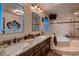 Bathroom with double sinks, granite counters, decorative mirrors, and a large soaking tub at 8396 Garnet Canyon Ln, Las Vegas, NV 89129