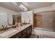 Bathroom with double sinks, granite counters, decorative mirrors, and a large soaking tub and shower at 8396 Garnet Canyon Ln, Las Vegas, NV 89129