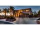 Elegant two-story home at dusk with palm trees, three-car garage and a circular driveway at 8396 Garnet Canyon Ln, Las Vegas, NV 89129